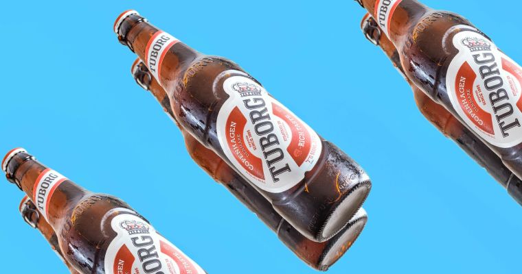 Tuborg beer bottles against blue background.