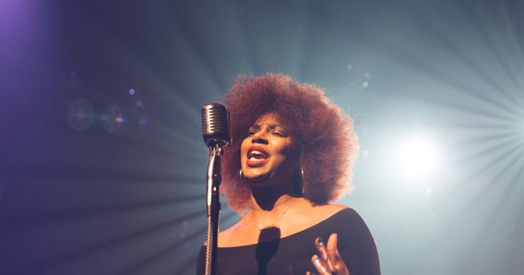 A woman singing into a microphone on stage.