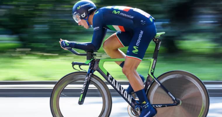 Cyclist in blue and green jersey rides a Canyon.