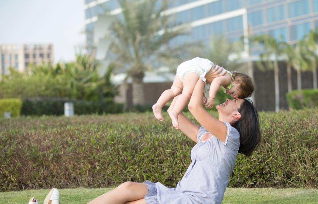 Woman holding baby girl in the air.