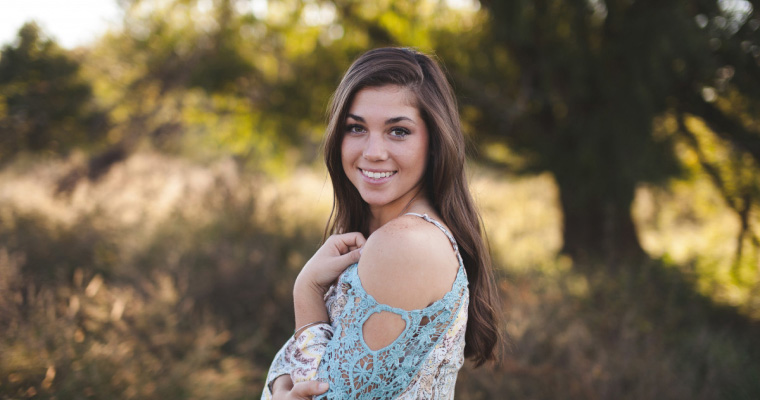 Woman with long brown hair smiles outdoors.