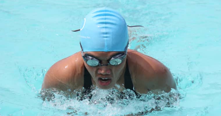 Swimmer in blue cap with goggles in pool.