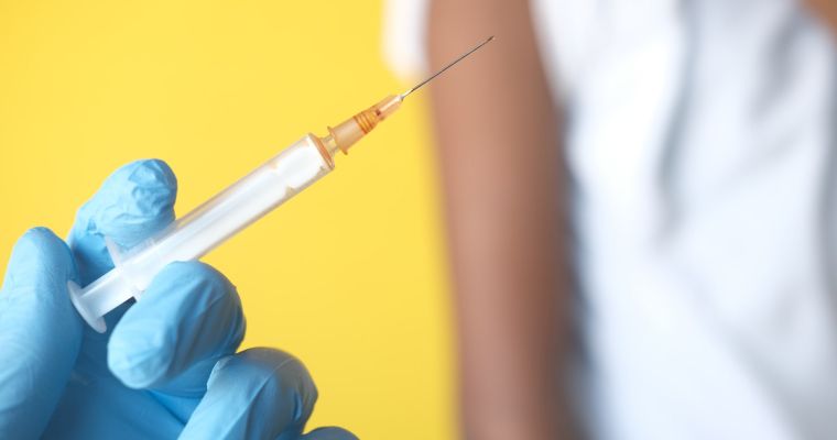 Close-up of a gloved hand holding a syringe.